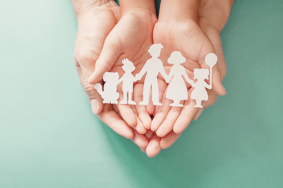 Adult and children hands holding paper family cutout, family hom